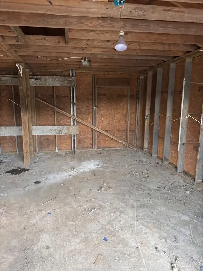 An emptied timber garage with bare stud walls and a swept floor