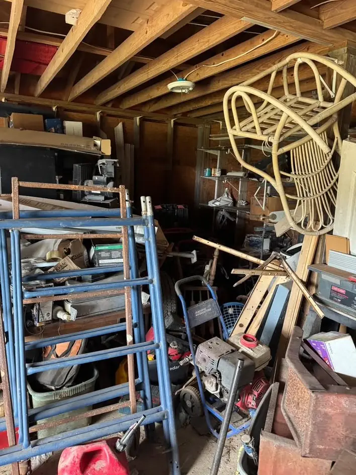 A garage packed with metal shelving, a rattan chair and stored tools