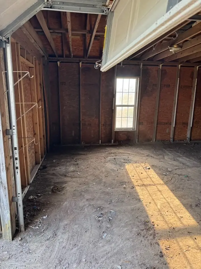 An emptied timber garage lit through a single window after clearing