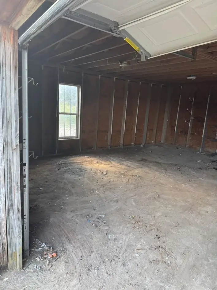 An emptied timber garage with the door open to the yard