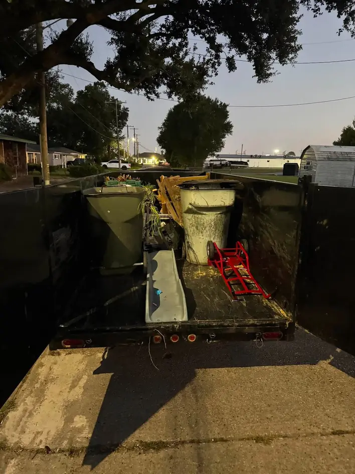A dump trailer loaded with a removed toilet and building debris