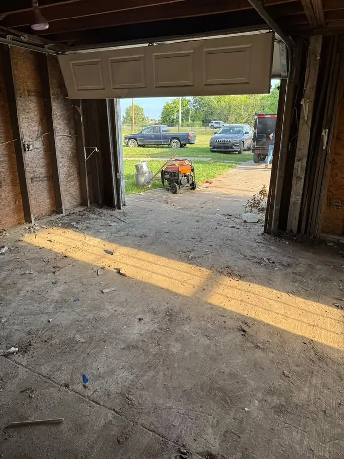 Inside an emptied timber garage looking out through the open door