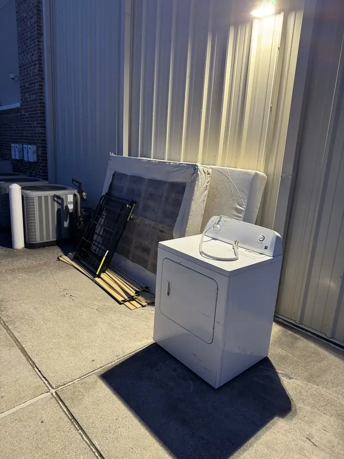 A washing machine and stacked panelling set out on the pavement beside a commercial building