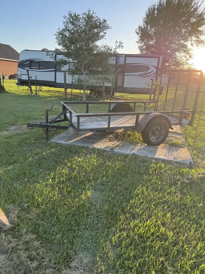 Empty Klutter Krewe utility trailer parked on a concrete pad before a debris haul