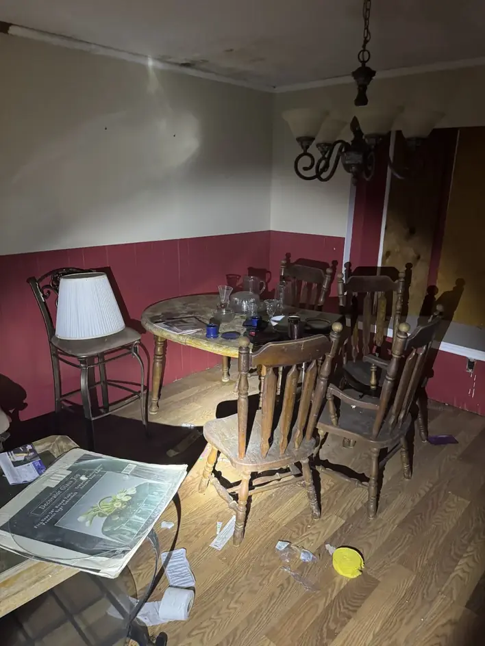 A dining room with table, chairs, lamps and framed pictures being sorted during an estate cleanout