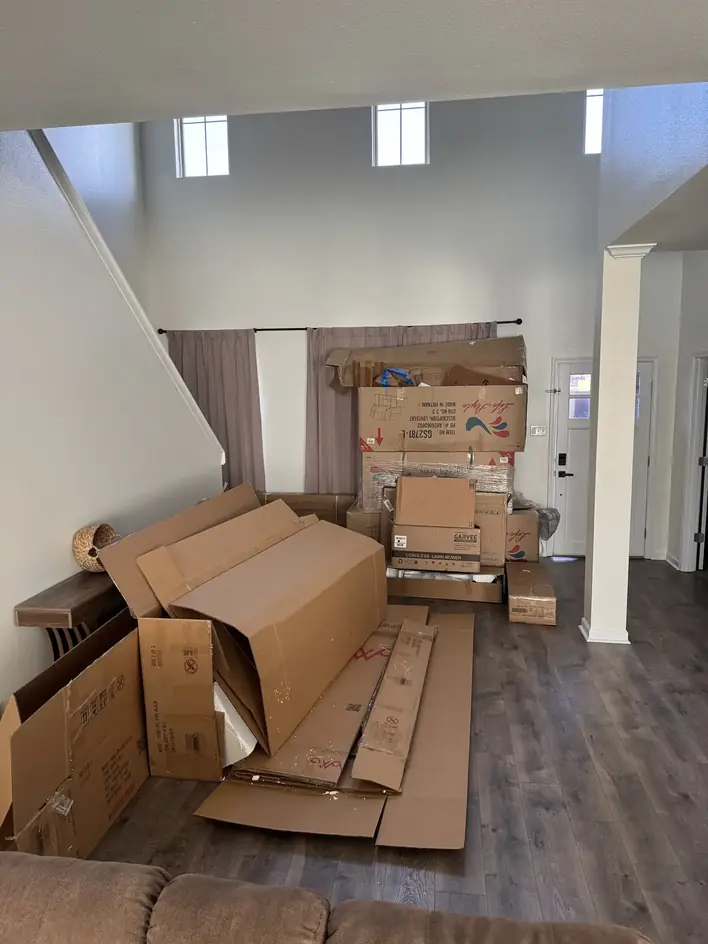 Flattened moving boxes and packing debris stacked across a living room floor
