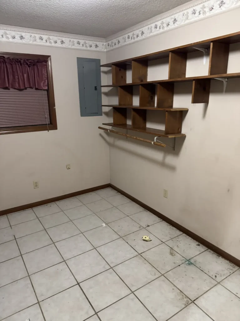 Emptied room with built-in wooden shelving and a swept tile floor
