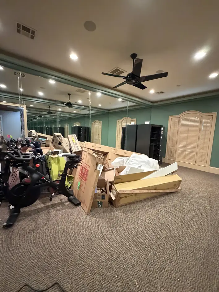 Exercise equipment and flattened boxes staged for removal in a mirrored studio