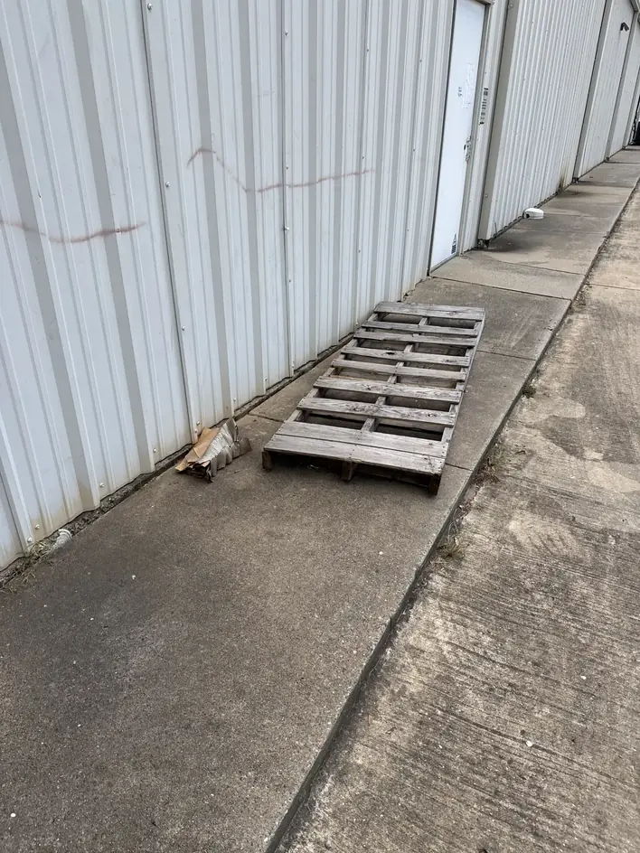 Wooden pallet set out against a metal building for collection