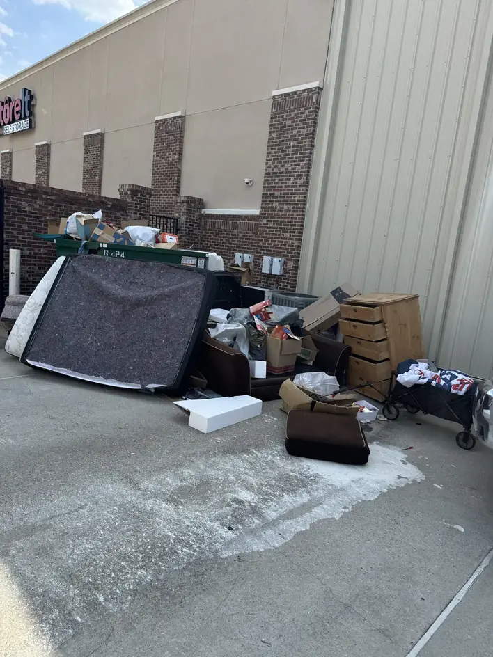 Mattress, cabinets and household items dumped beside a commercial building