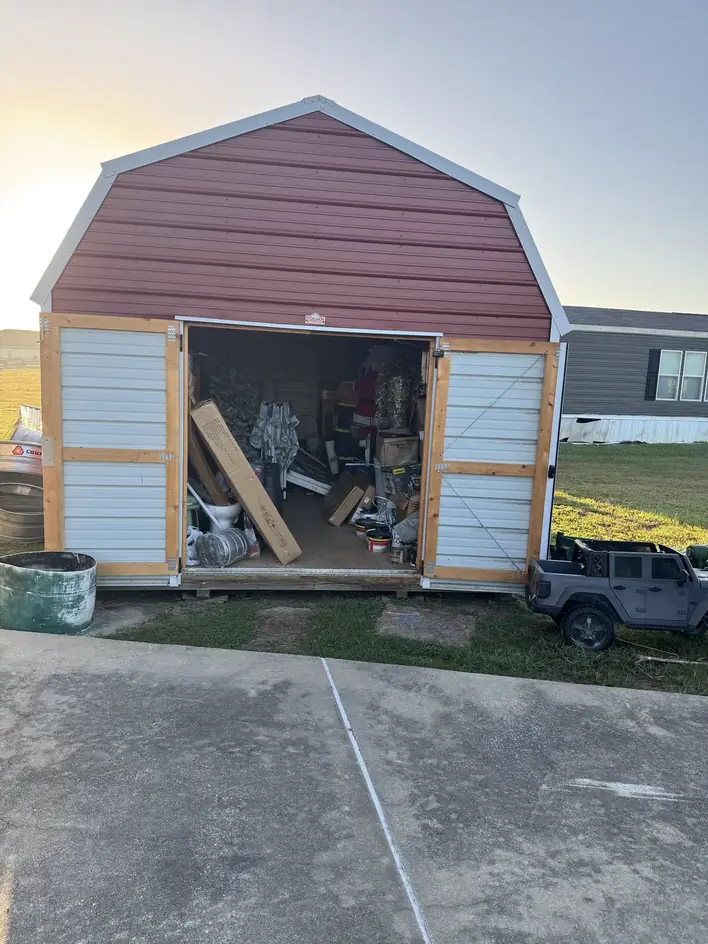 Backyard storage building filled to the doors, seen from the driveway
