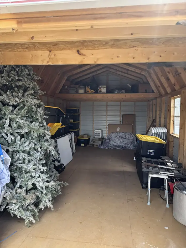 Inside the storage building before clearing, with a Christmas tree and stacked bins