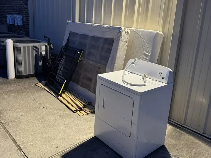 A washing machine and stacked panelling set out on the pavement beside a commercial building