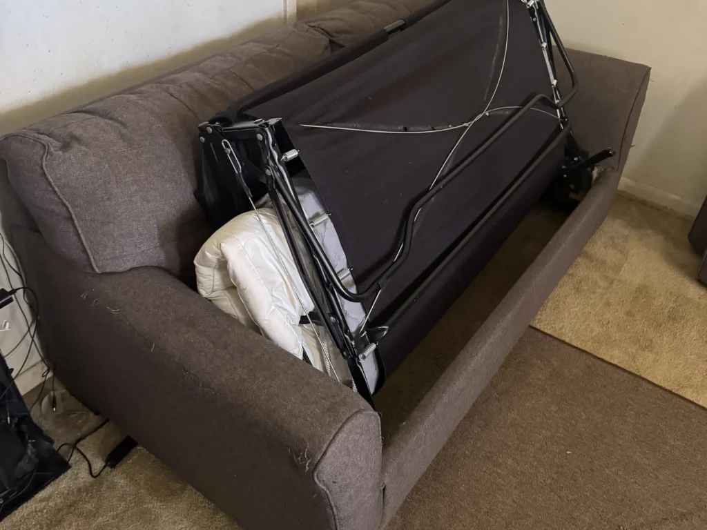 A sofa bed with its folding frame pulled out in a Sulphur home before removal